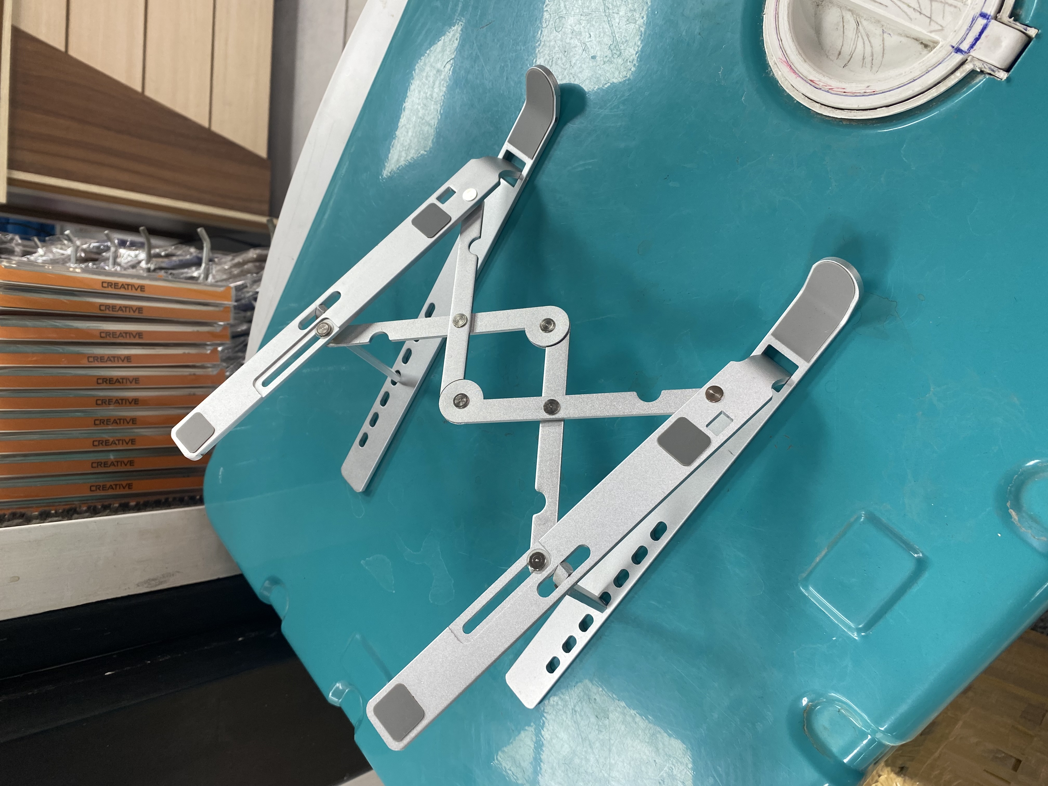 استند فلزی نقره‌ای قابل تنظیم لپ‌تاپ و تبلت روی میز کار